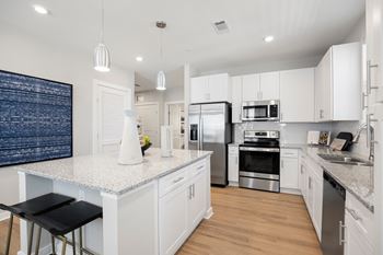 a large kitchen with white cabinets and stainless steel appliances